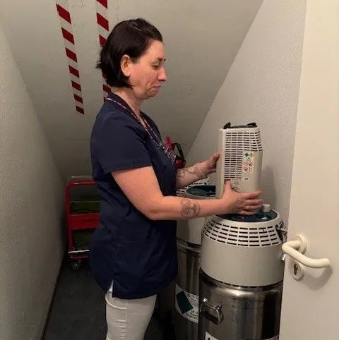 Frau füllt eine Sauerstoffflasche in einem engen Raum auf.